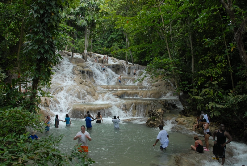 Tourists climbing the magnificent Dunn's River Falls surrounded by tropical foliage